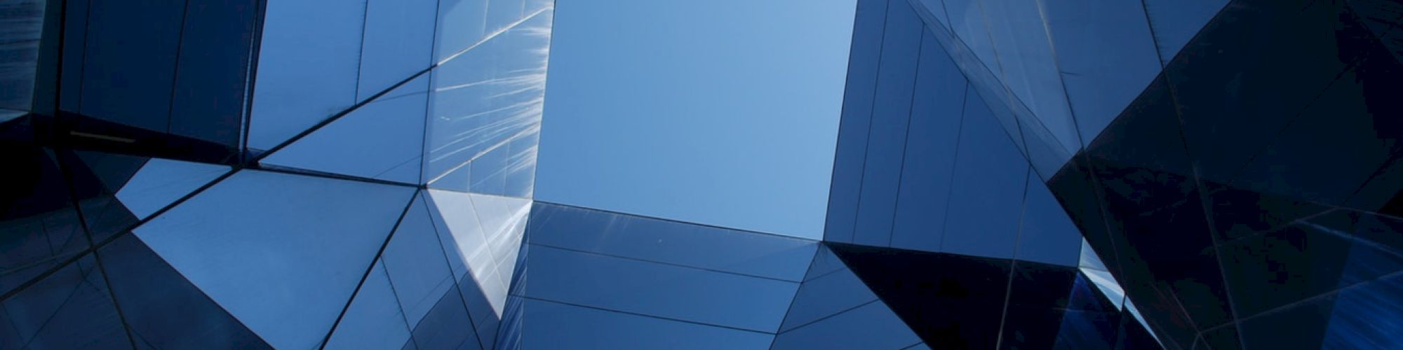 Geometric glass structures form a symmetrical pattern against the sky, creating a modern architectural design.