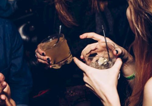 People enjoying a night out, holding drinks and laughing, captured in a lively social setting.