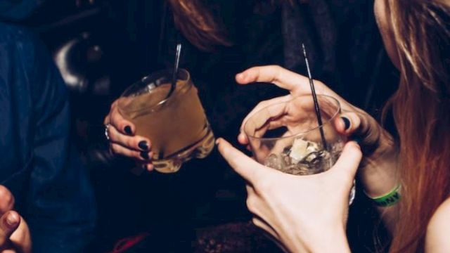 People enjoying a night out, holding drinks and laughing, captured in a lively social setting.