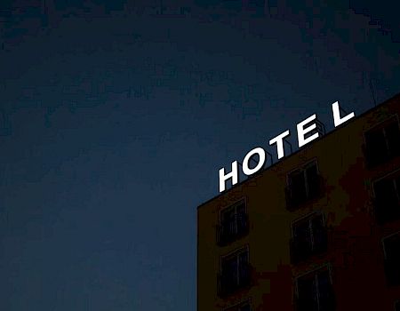A building with a "HOTEL" sign missing the letter "T" against a dark evening sky.