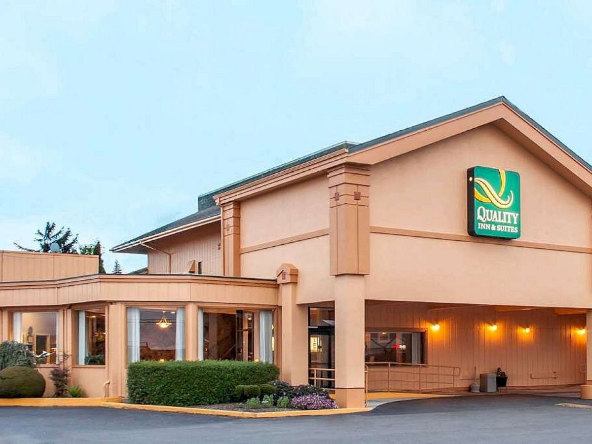 A hotel building with a "Quality Inn & Suites" sign, featuring a tan exterior and landscaped surroundings.