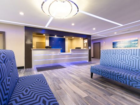 The image shows a modern lobby with patterned seating, a reception desk, and contemporary lighting.