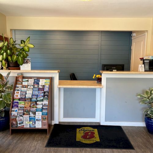A reception area with a counter, brochures, plants, and a welcome mat. It has a blue accent wall and a coffee machine.